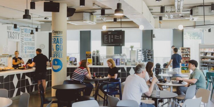 The center has a community kitchen, lounge areas, free parking, 24/7 access, privacy pods, complimentary tea and coffee, an on-site café, and full printer access.