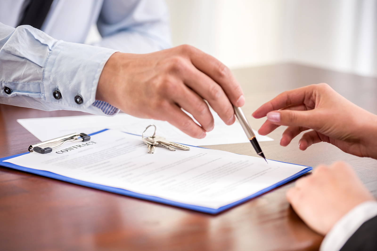Young woman is signing financial contract with male realtor. Close-up.